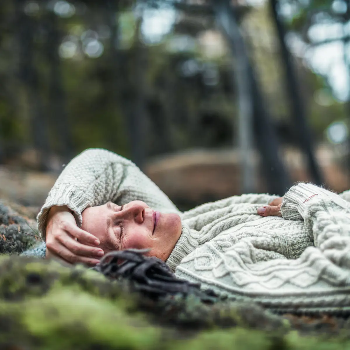 Person som slappnar av i en stickad tröja ute i naturen